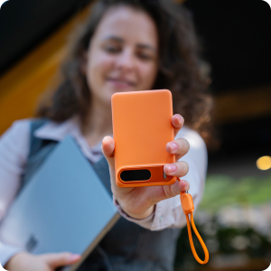 Pomarańczowy powerbank 3mk incharge Genesis Qi 2.2 z paskiem na nadgarstek, trzymany w dłoni