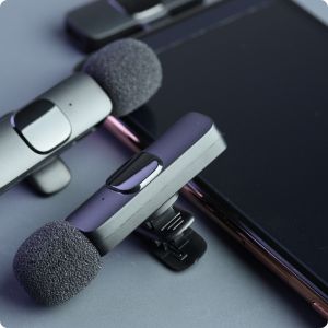 Jak wybrać mikrofon krawatowy bezprzewodowy dwa mikrofony krawatowe połączone obok smartfona na szarym tle.