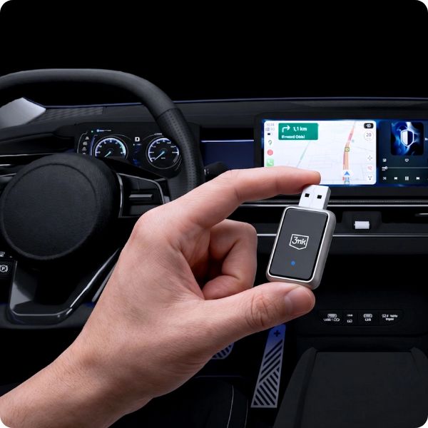 Adaper bezprzewodowy Carplay i Android Auto trzymany przez użytkownika w dłoni. W tle wnętrze samochodu.